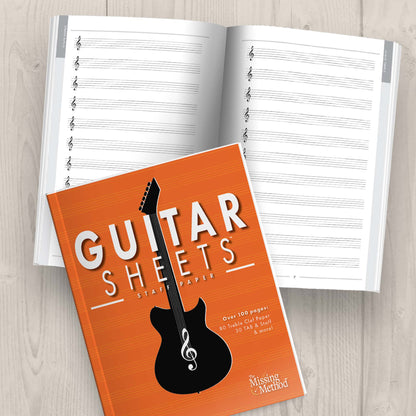 Guitar Sheets Staff Paper, Paperback book from The Missing Method for Guitar, displayed open on tabletop, showing both the front cover and interior pages. Copyright 2024 Tenterhook Books, LLC.