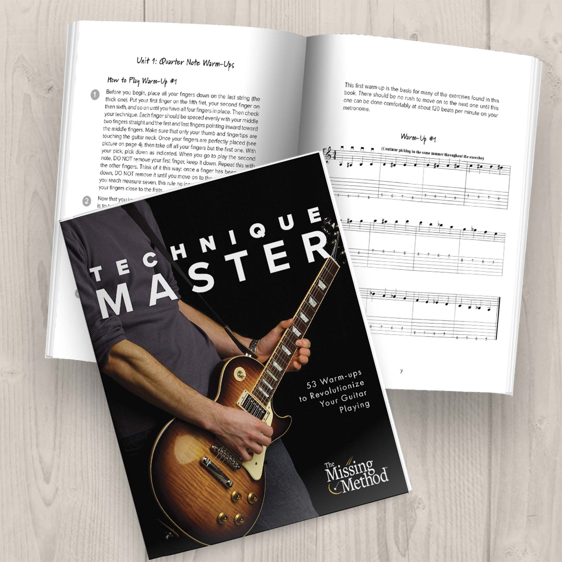 Technique Master from The Missing Method for Guitar. Image of two copies of the book on a tabletop, one open and displaying the first part of the first set of warm-ups. The second book closed, displaying the front cover.